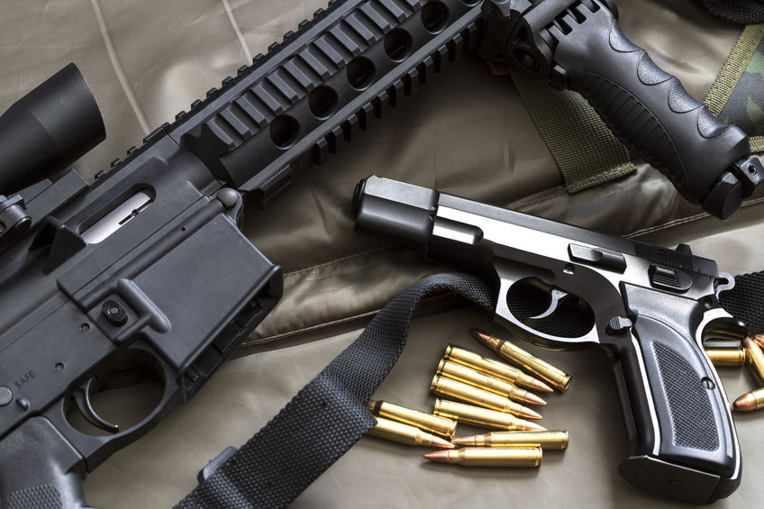 Rifle and Handgun with Ammunition on Brown Backdrop