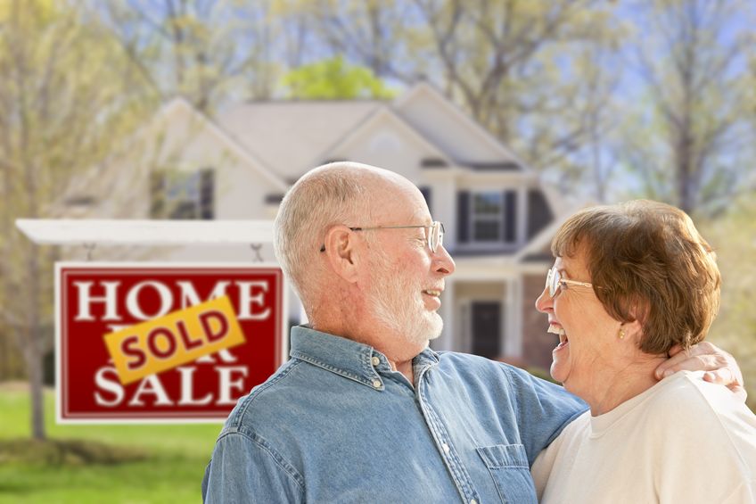 Senior couple standing outside of their newly sold home
