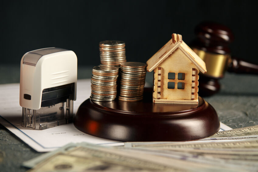 A row of coins on a small house model and a law auction hammer