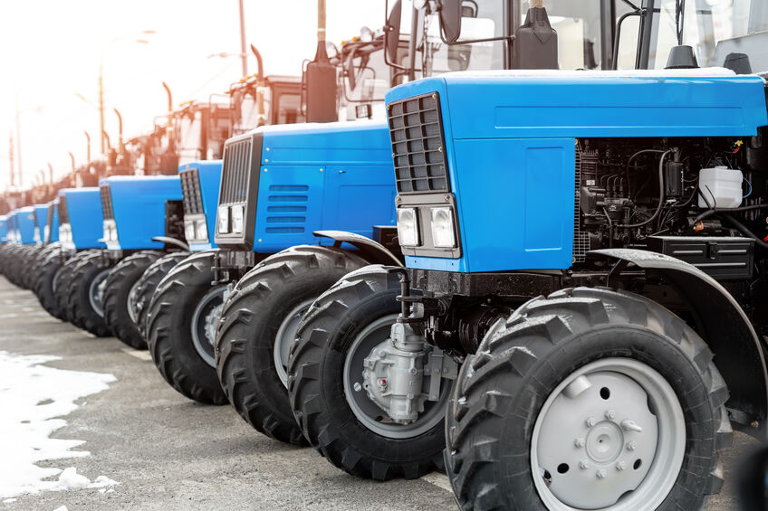 Many different tractors standing in row at auction.